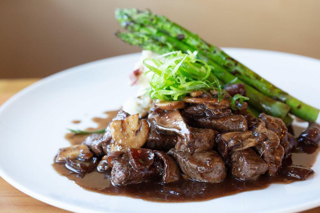 Steak Tips Cabernet · Shoulder steak tenderloin cooked with cippolini onions, mushrooms in a red wine demi glaze sauce. Served with mashed potatoes and asparagus.