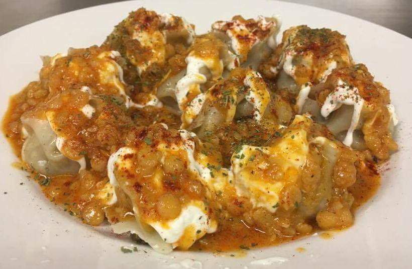 Mantoo · Steamed afghani dumplings stuffed with ground beef, onions, and spices, topped with garlic yogurt, split peas sauce, and dried mint.