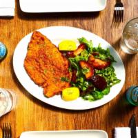 Chicken Milanese · Argentina. Breaded chicken breast cutlet served with tomato and arugula salad.