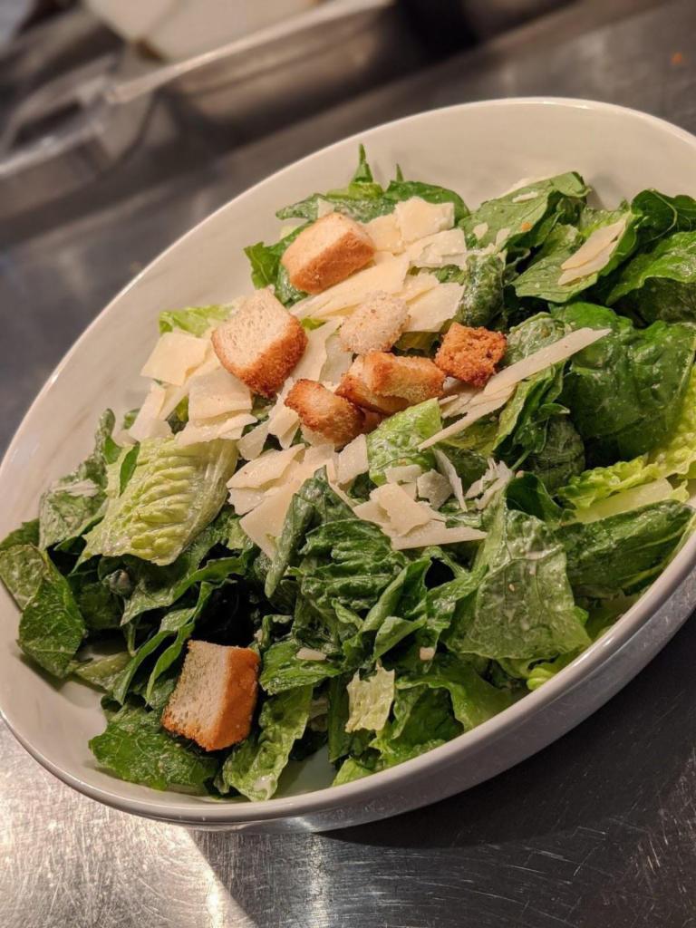 Caesar Salad · Crispy romaine leaves, shredded Parmesan, fresh croutons, and Caesar dressing.