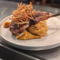 Tomahawk Pork Chop · Grilled to perfection on a bed of chipotle mashed potatoes and crispy onion strings.