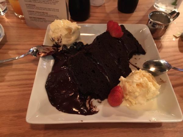 Clementine's Chocolate Mud Cake · A massive slice of chocolate cake served warm, topped with a strawberry and blueberries.