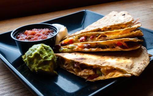 Quesadilla · Giant tomato-basil tortilla loaded with pepper jack cheese, red beans, bell peppers, and your choice of chicken or spiced ground beef.