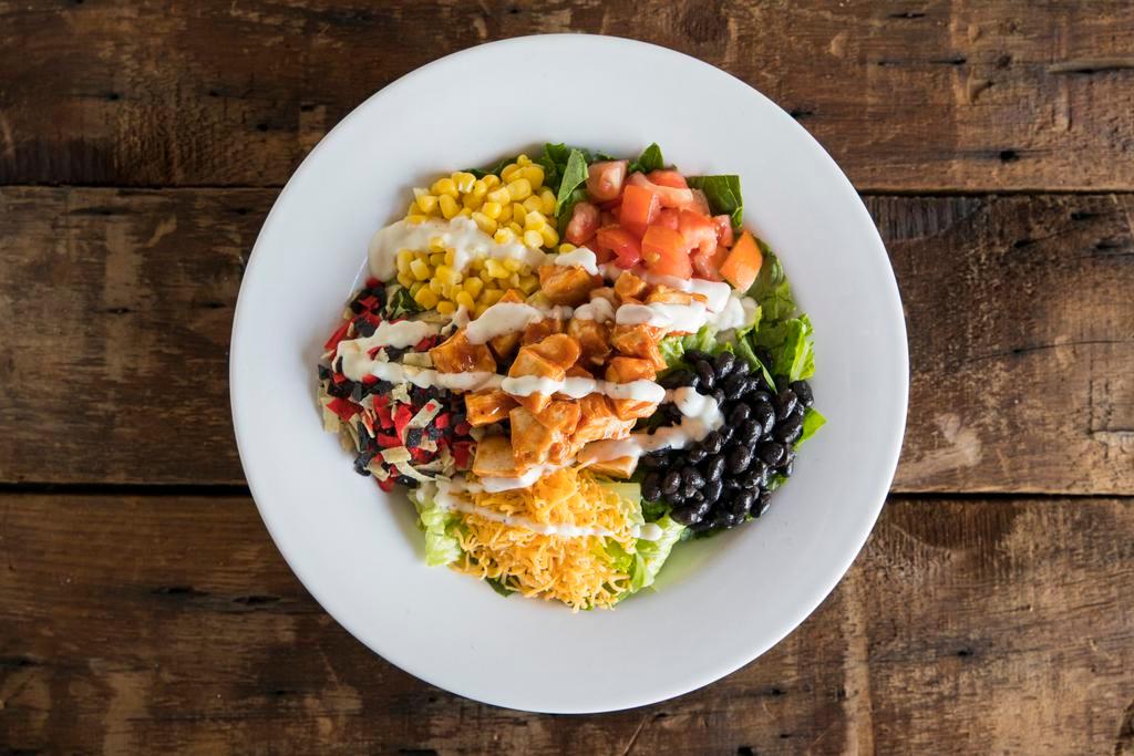 Dr. Ranchero Salad · Crisp romaine, sweet corn, tomatoes, cheddar, black beans, crispy tortilla chips, grilled BBQ chicken and ranch dressing.