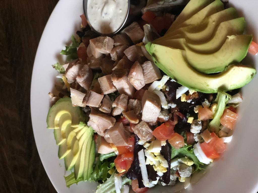 Smoked Chicken Cobb · Mixed greens topped with house smoked chicken, bacon, hard-boiled egg, blue cheese crumbles, tomatoes and avocado, served with your choice of dressing.