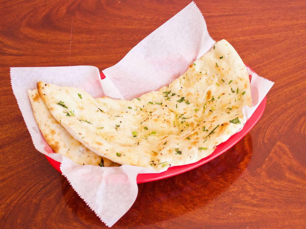 Garlic Naan · Soft leavened bread with garlic and cilantro leaved prepared in clay oven.