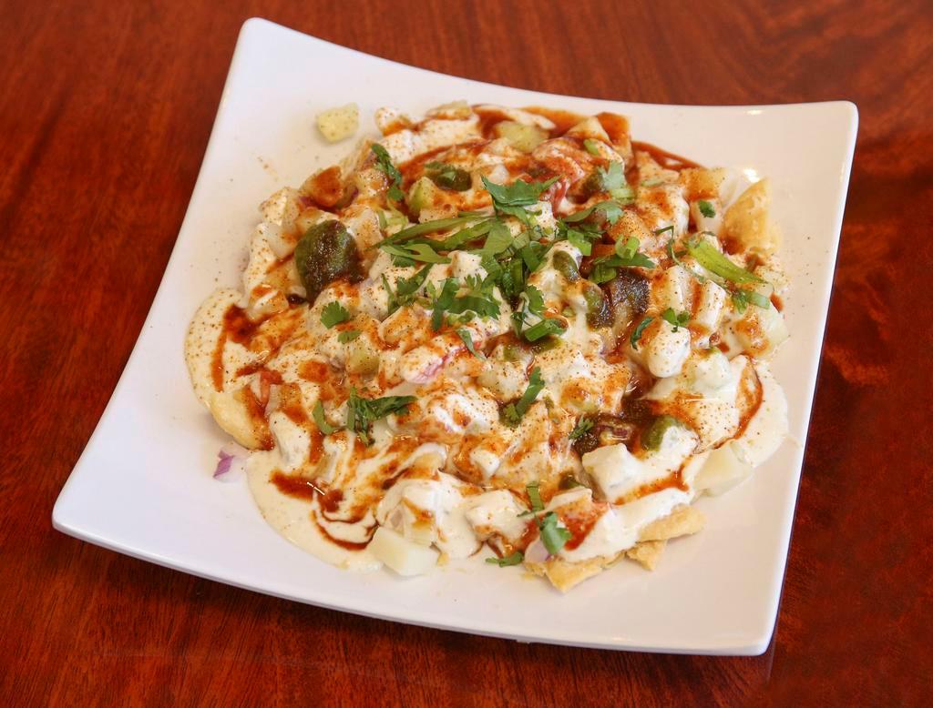 Papri Chaat · Indian style fried tortilla chips topped with boiled potatoes, chickpeas, yogurt and green chutney.