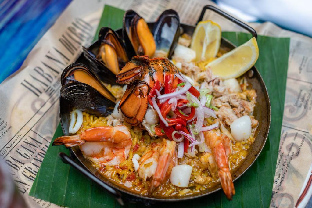 Paella Marinera · Jumbo shrimp, Maine lobster tail, mussels, squid, Baja Bay scallops, claw crabmeat, saffron long grain rice, and roasted piquillo pepper salad.