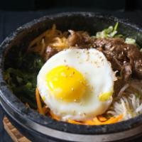 Beef Okdol Bibimbap · Rice with assorted vegetables and beef topped with an egg, served in a hot stone pot with re...