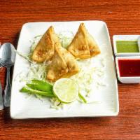 Vegetable Samosa · Served traditionally with channa masala, chopped onions, cliantro leaves smothered with swee...