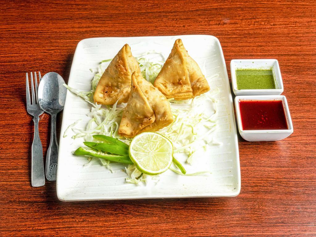 Vegetable Samosa · Served traditionally with channa masala, chopped onions, cliantro leaves smothered with sweet chutney and chilled light yogurt.