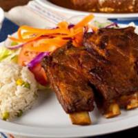 Costilla de Puerco Enchilada · Critics favorite. Chile-marinated fried or grilled pork ribs. Served with rice, black beans,...
