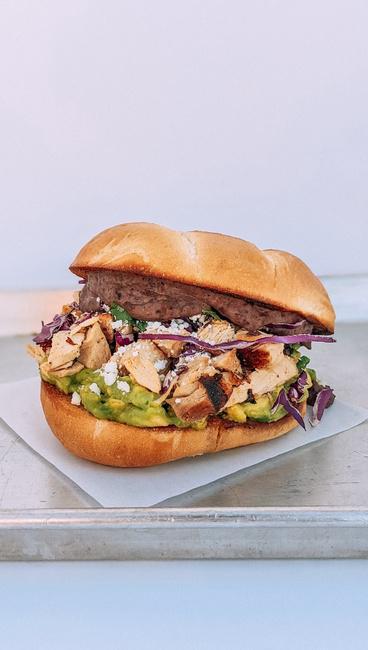 BRAISED CHICKEN TORTA · Refried Black Beans, Smashed Avocado, Red Cabbage Salad, And Queso Fresco