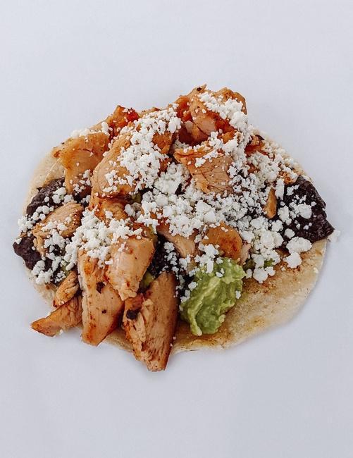 BRAISED CHICKEN TACO · Braised Chicken,  Smashed Avocado, Black Bean Refritos, Queso Fresco, And Your Choice Of Salsa. Served On Gluten-Free White Corn Tortillas