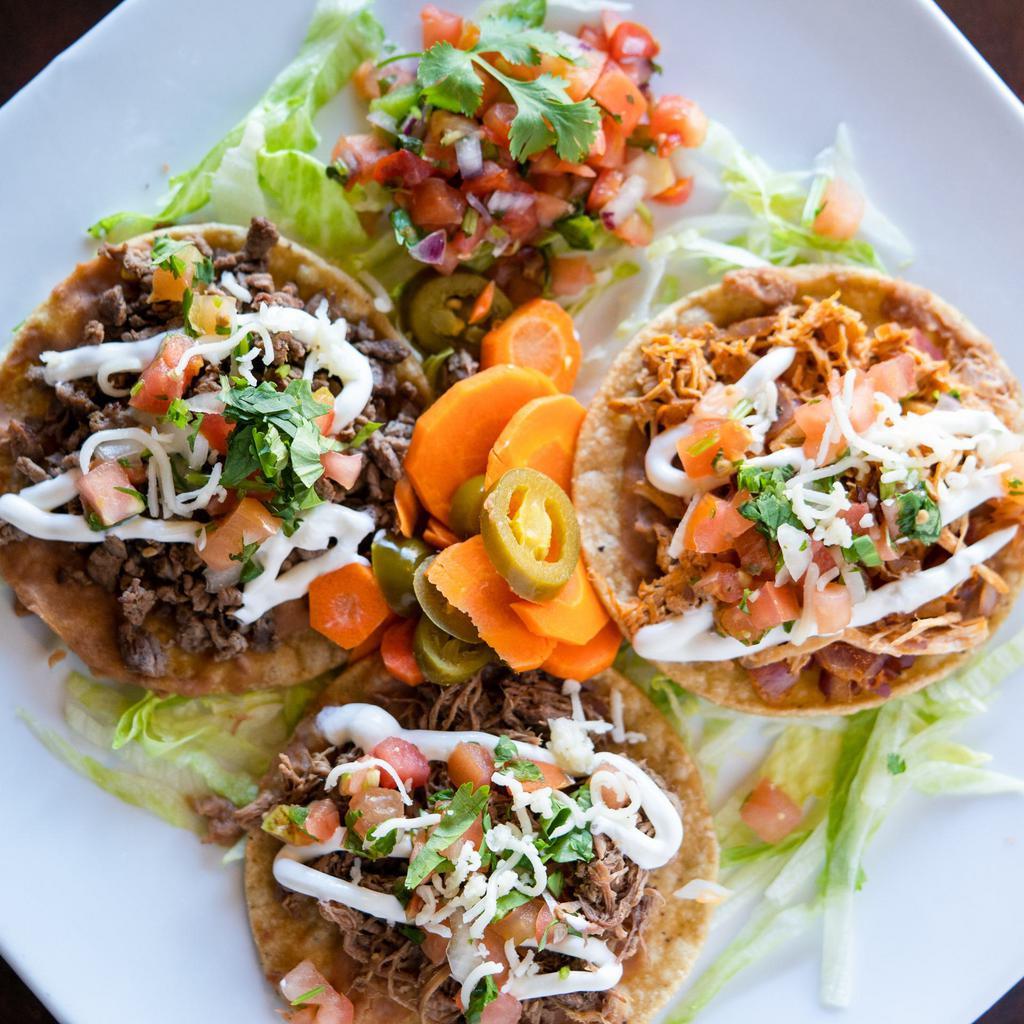 Dinner Tostadas · A crispy flat tortilla. Topped with refried beans, lettuce, cotija cheese, tomato sauce, and your choice of meat.