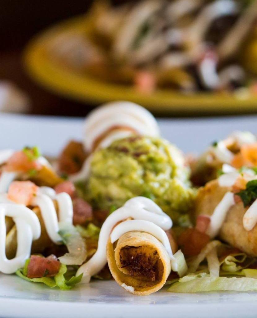Taquitos Dorados de Papa · 5 hard shell potato taquitos topped with shredded lettuce, Cotija cheese, and salsa.