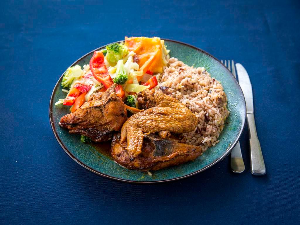 Brown Stew Chicken Full Meal · Brown stew chicken served with rice and peas and steamed vegetables.