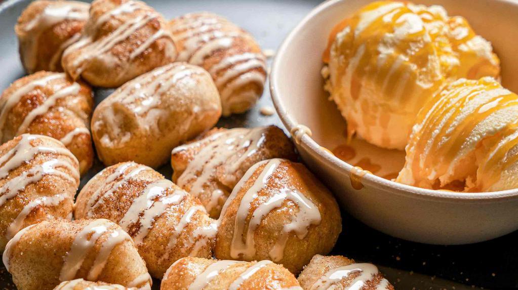 Cinnabites · Freshly baked cinnamon & sugar bites drizzled with vanilla sauce, & served with ice cream topped with caramel sauce.