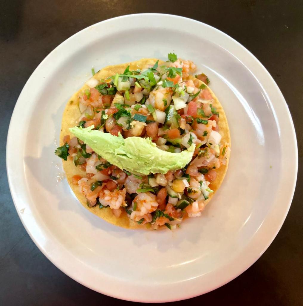 Ceviche Tostada · Prawns marinated in lime juice with pico de gallo and avocado sliced on top of a homemade corn tostada.
