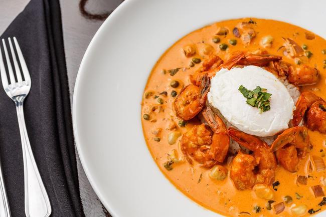 Chupe de Camarones · A peruvian seafood favorite, creamy shrimp chowder made with aji panca chili, served with garlic jasmine rice and a poached egg on top.