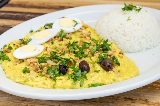 Aji de Gallina · A creamy stew made with shredded chicken breast cooked with Aji Amarillo chili, Parmesan cheese, cream, garnished with walnuts, olives, eggs, and cilantro, served with potato slices and garlic Jasmine rice.