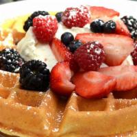 Tropical Waffle · Topped with strawberries, bananas, blueberries, whipped cream, and chocolate syrup.