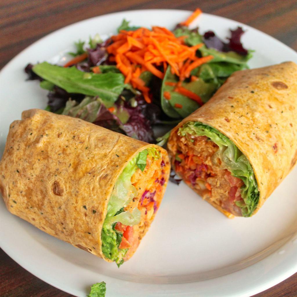 Buffalo Soycurl Wrap · Buffalo smothered soy curls, crispy romaine lettuce, diced tomatoes, and cabbage-apple coleslaw inside a flour tortilla comes with a side salad served with cilantro lime vinaigrette.