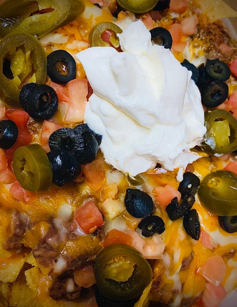 Nacho Supreme · Crispy tortilla chips piled high with your choice of grilled chicken or seasoned ground beef, refried beans, cheddar cheese and sour cream, homemade salsa.