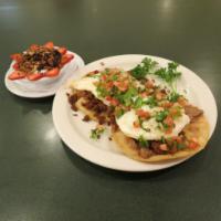 Chorizo Tostados · 2 crispy corn tortillas with grilled chorizo sausage, eggs, and refried beans topped with pi...