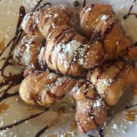 Sweet Knots · Twisted dough knots drizzled with chocolate and dusted with powdered sugar.