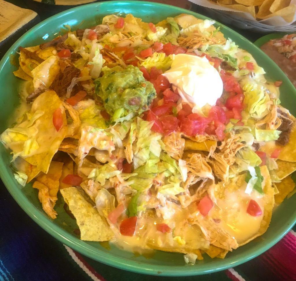 Nachos Supreme · Crisp tortilla chips loaded with chicken, ground beef, shredded beef, beans and cheese dip sauce. Topped with lettuce, tomatoes, guacamole and sour cream.