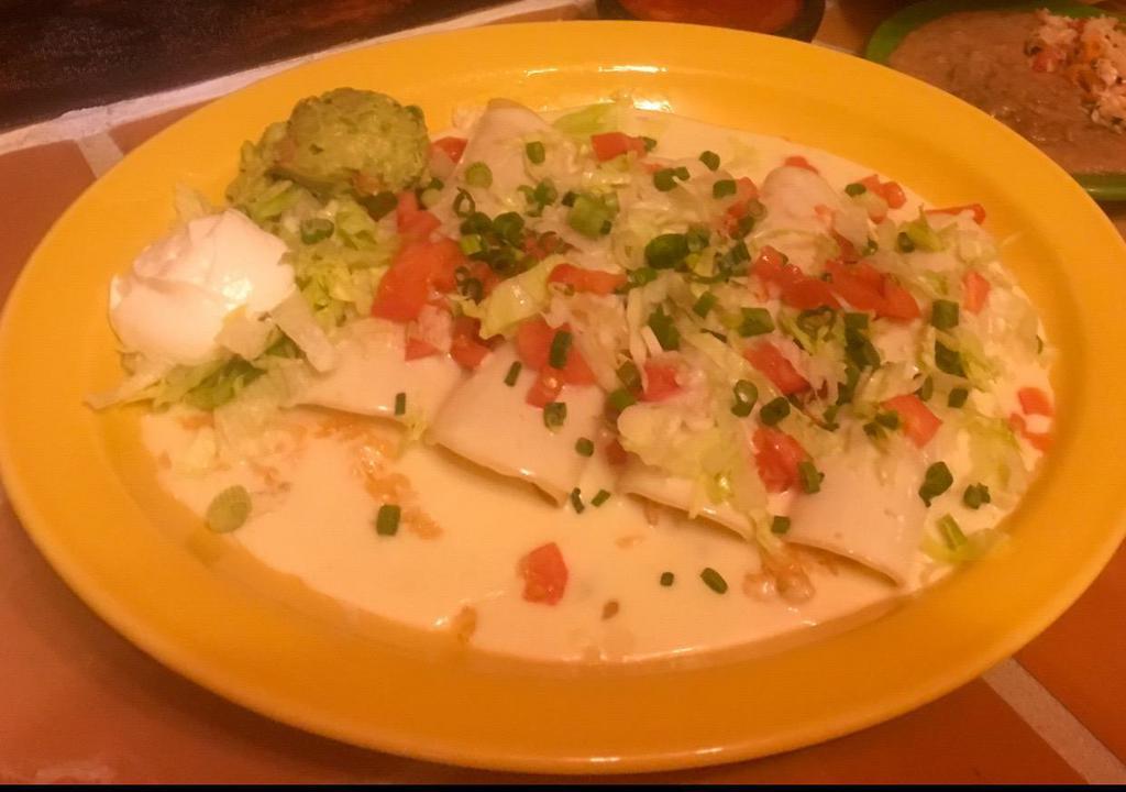 Enchiladas Adelitas · 4 enchiladas: 1 chicken, 1 shredded beef, 1 ground beef and 1 cheese. Topped with cheese dip sauce, lettuce, tomatoes, sour cream and guacamole. No rice or beans.
