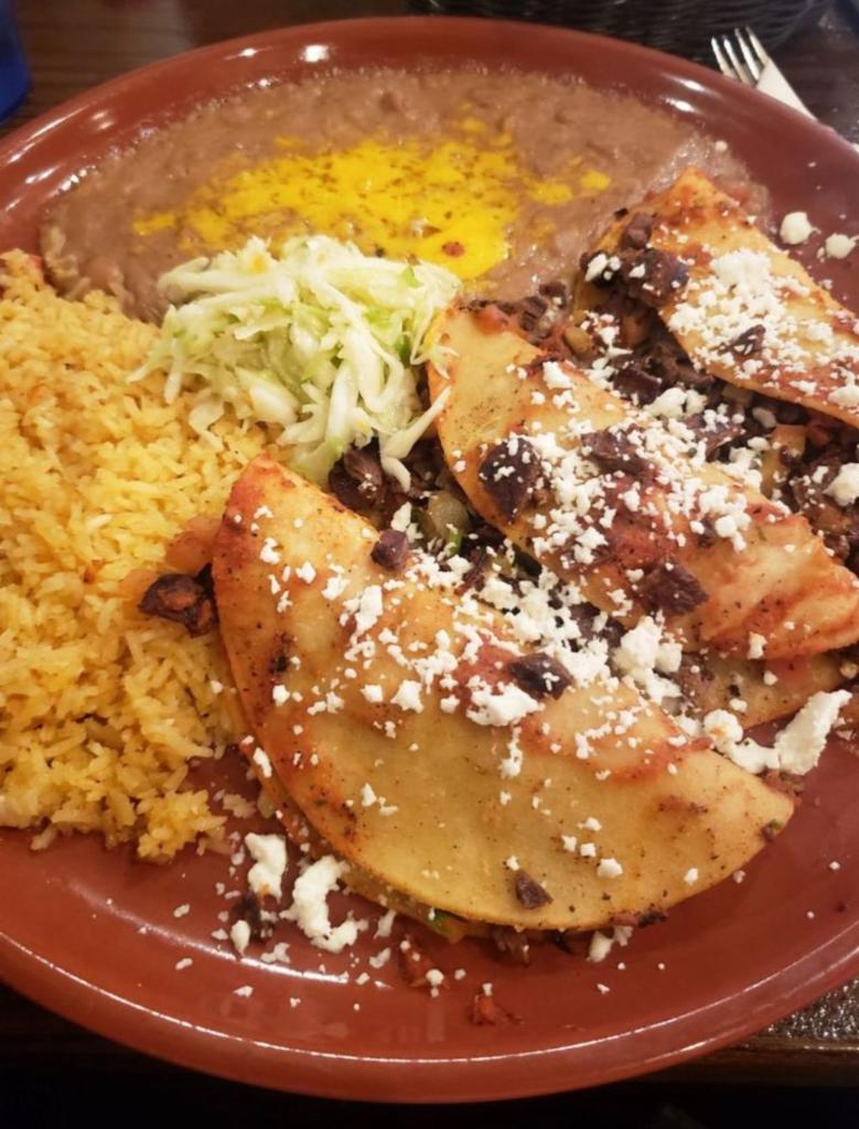 Tacos al Carbon · Flame broiled skirt steak slices and folded into a soft corn tortillas with Mexican salsa, topped with ranchero cheese. Served with rice and beans.