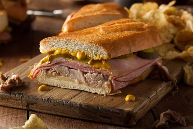 Sandwich Cubano · Sandwich cubano con jamon, queso suizo, cerdo, mostaza, mayonesa y pepinillo, servido en pan cubano.