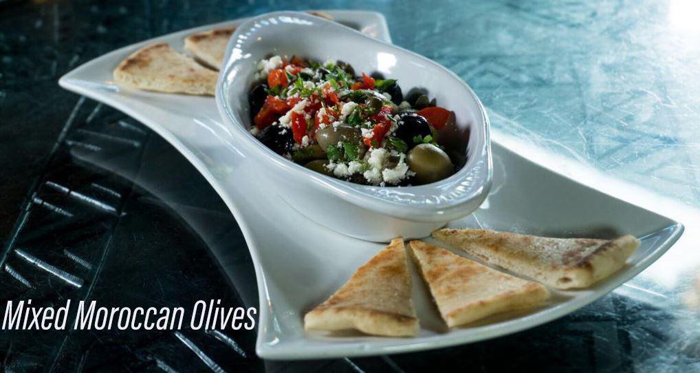 Mixed Moroccan Olives · A combination of bitter black oil cured olives and green olives topped with feta, roasted red peppers and capers.