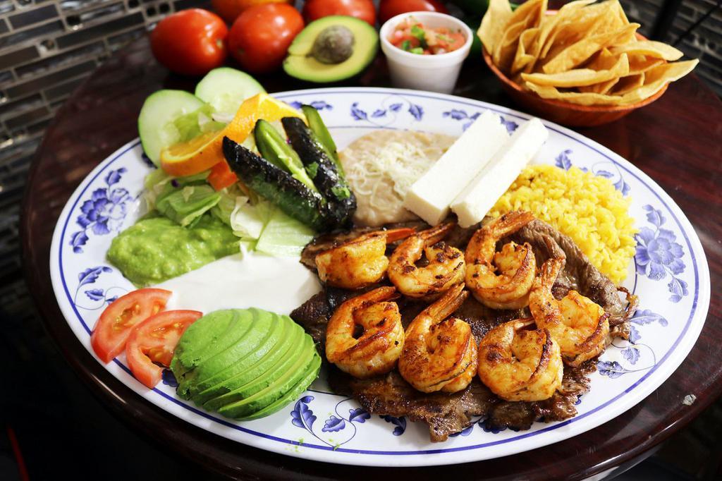 Carne Asada con Camaron · Slightly spiced beef steak and shrimp slowly grilled, served with rice, refried beans, salad, fresh guacamole, and sour cream.