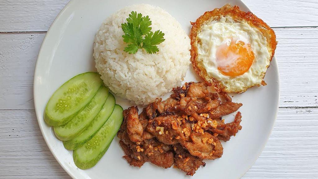 Bangkok Garlic · Stir meat with fresh garlic, onion, scallion in brown sauce and fried egg on top served with slice cucumber, clear soup and Thai sriracha 

