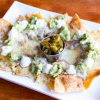 Nachos · Homemade tortilla chips individually layered with refried beans, melted cheese, guacamole, s...