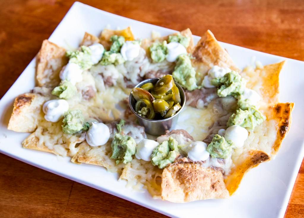 Nachos · Homemade tortilla chips individually layered with refried beans, melted cheese, guacamole, sour cream and a side of jalapenos.