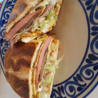 Torta Cubana · Ham, bacon, franks, head cheese, milanesa, and fried egg topped with queso fresco, onions, t...