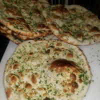 Garlic Naan · Round shaped white bread baked in tandoor (clay oven) with a touch of garlic and butter. 