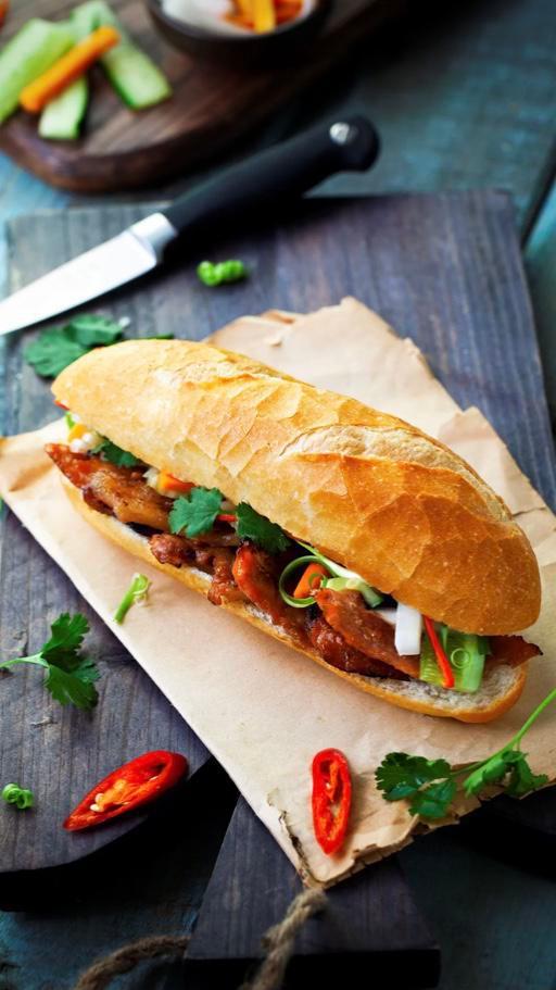 Grilled Pork Banh Mi · Vietnamese baguette, grilled pork, pork pate, mayo, cucumber, pickled carrots and daikon, jalapenos, and cilantro. Served with your choice of shrimp crackers or vegan Vietnamese coleslaw.
(COLESLAW CONTAINS CASHEW)