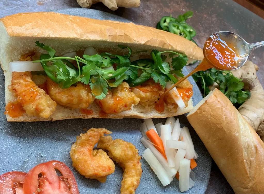 Viet Shrimp Po Boy Banh Mi · Vietnamese baguette, shrimp tempura, mayo, cucumber, pickled carrots and daikon, jalapenos, and cilantro. Sweet chili sauce on the side. Served with your choice of shrimp crackers or vegan Vietnamese coleslaw.
(COLESLAW CONTAINS CASHEW)

