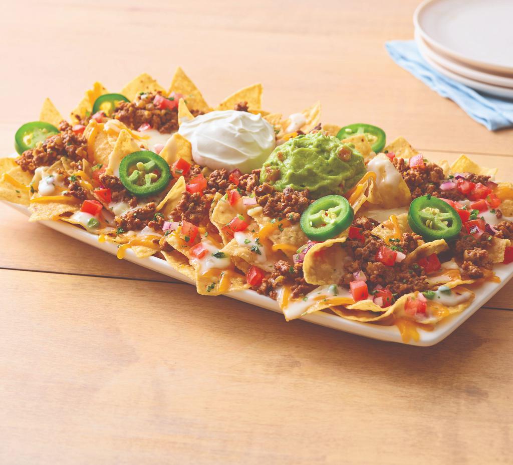 Neighborhood Beef Nachos · Freshly made white corn tortilla chips are topped with taco-seasoned ground beef, queso blanco, a blend of melted Cheddar cheeses, house-made pico de gallo, fresh jalapeños, chopped cilantro, sour cream and guacamole.