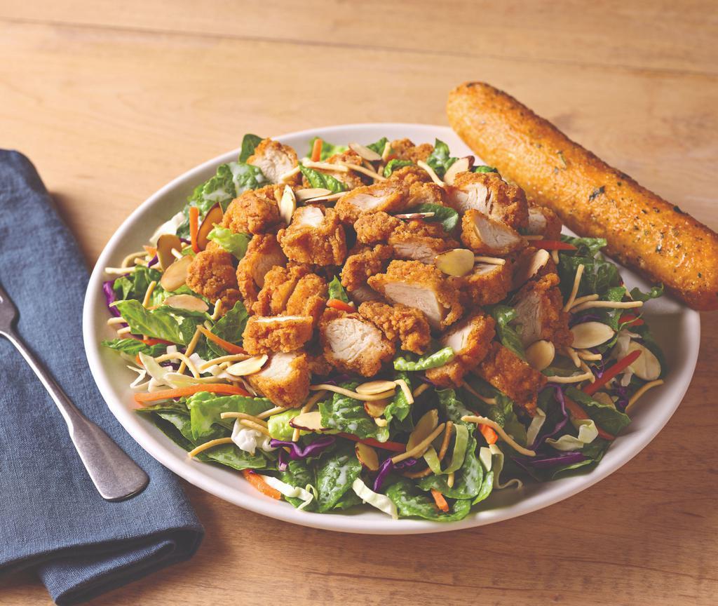 Oriental Chicken Salad · A long-running favorite, crispy breaded chicken tenders top a bed of Asian greens, rice noodles and almonds tossed in our Oriental vinaigrette.