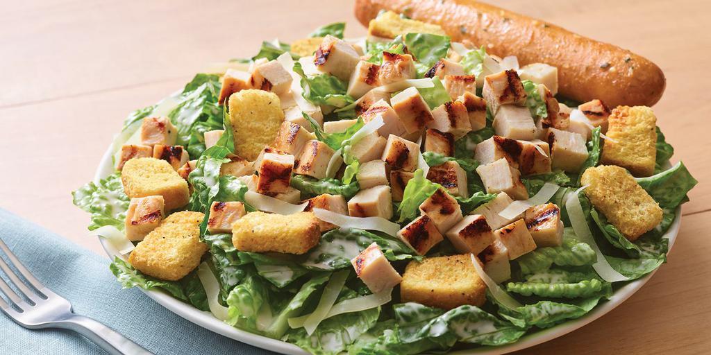 Grilled Chicken Caesar Salad · Crisp romaine tossed in garlic Caesar dressing and topped with grilled chicken, croutons and shaved Parmesan.