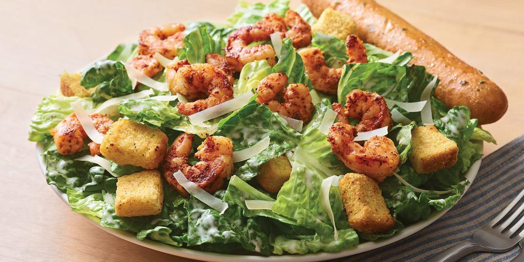 Blackened Shrimp Caeser Salad · Crisp romaine topped with blackened shrimp, croutons, shaved Parmesan and garlic Caesar dressing on the side. Served with a golden brown signature breadstick brushed with a buttery blend of garlic and parsley.