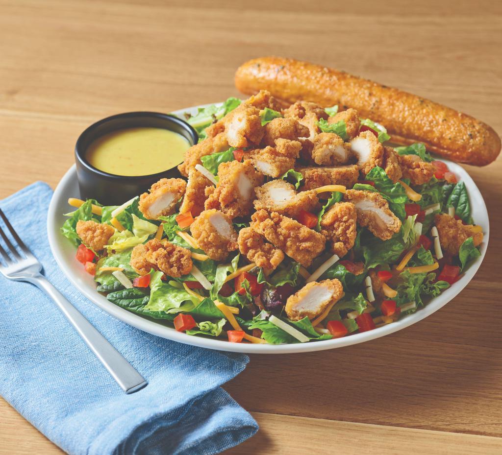 Crispy Chicken Tender Salad · A hearty salad with crispy chicken tenders on a bed of fresh greens topped with a blend of Cheddar cheeses, and tomatoes. Served with honey Dijon mustard dressing.