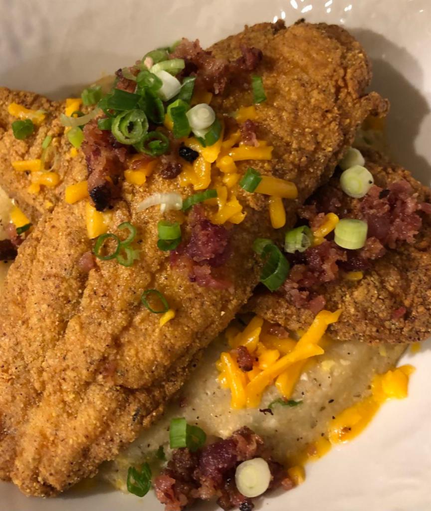 Darla’s Catfish ＆ Grits · Egg, Bacon and Green Onion Grit Cake, topped with Fried Catfish, Red and Green Peppers, Andouille Sausage and Cajun Andouille Butter Sauce with Cheddar Cheese and Green Onion and Bacon  toppings.
