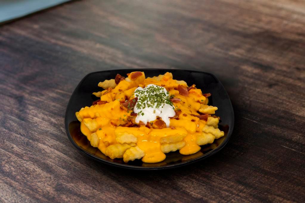 Smothered Cheese Fries · One-Half Pound of Straight-cut potato fries smothered in queso, topped with sour cream chives and sprinkled with bacon.